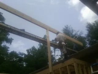 Carpenter setting a ridge beam over a new addition frame — Ice Dam Removal by Roofing Brothers in Saint Hedwig