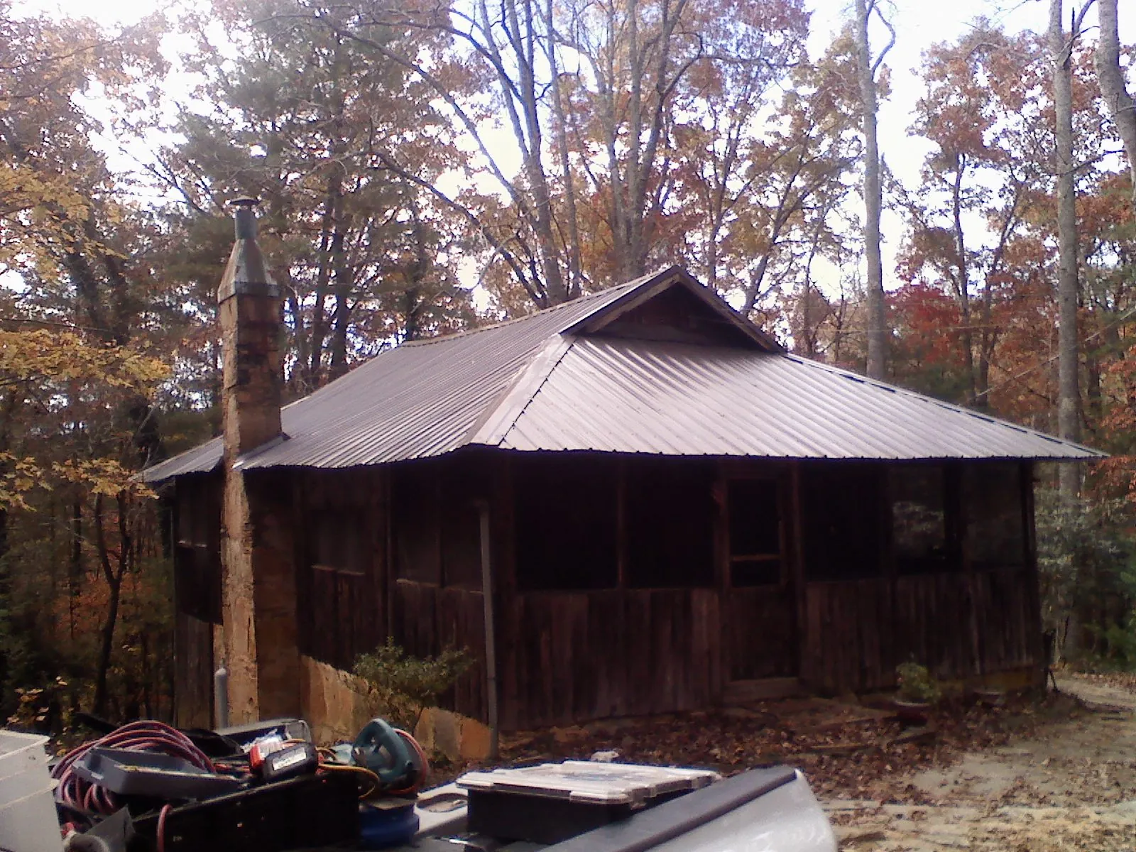 Brown metal hip roof on an old cabin with a stone chimney in Saint Hedwig