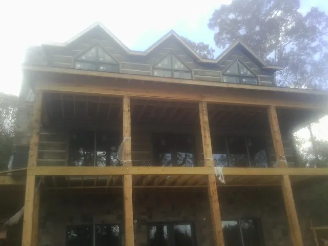 Dormers and porch framing on a large log home under construction — Roof Coating work by our crew in Saint Hedwig