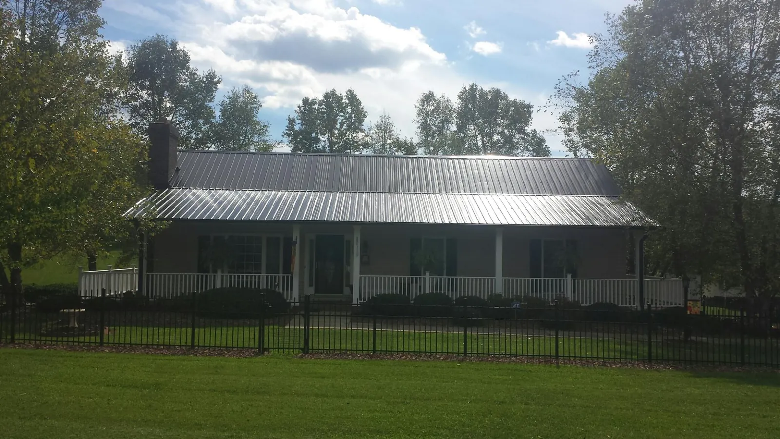 Gray metal roof on a brick ranch with a full width front porch — Gutter Guard Installation work by our crew in Saint Hedwig