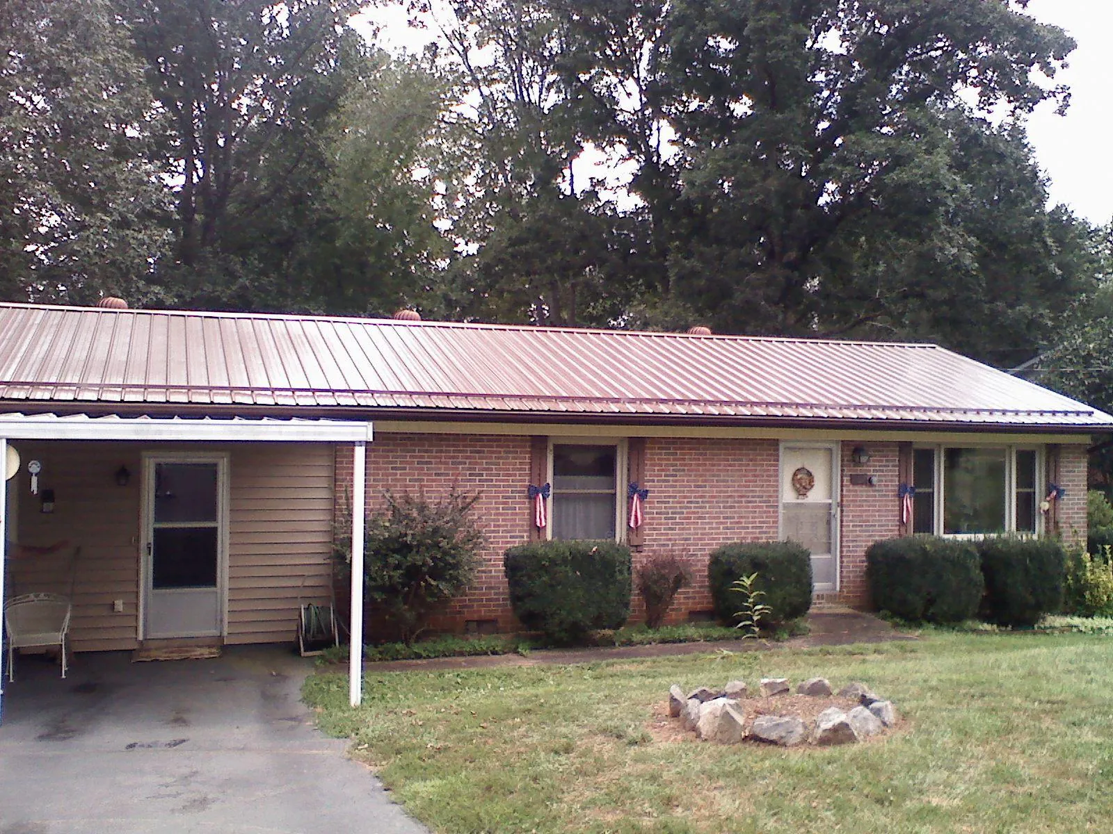 Bronze metal roof and carport on a brick ranch home — Roof Repair work by our crew in Saint Hedwig